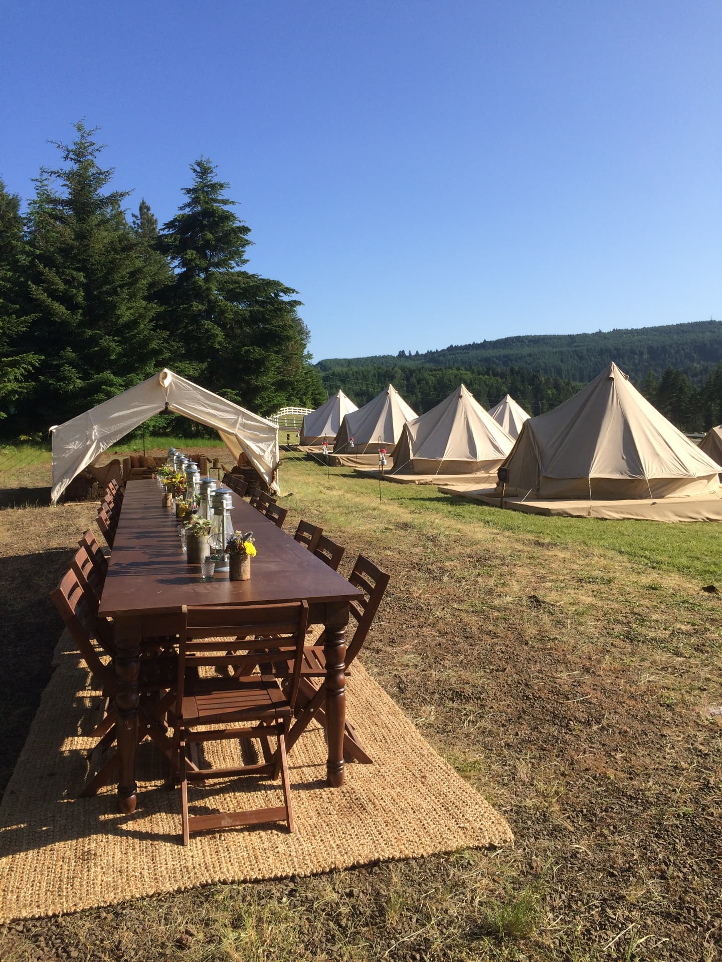 A long ranch table set among glamping tents