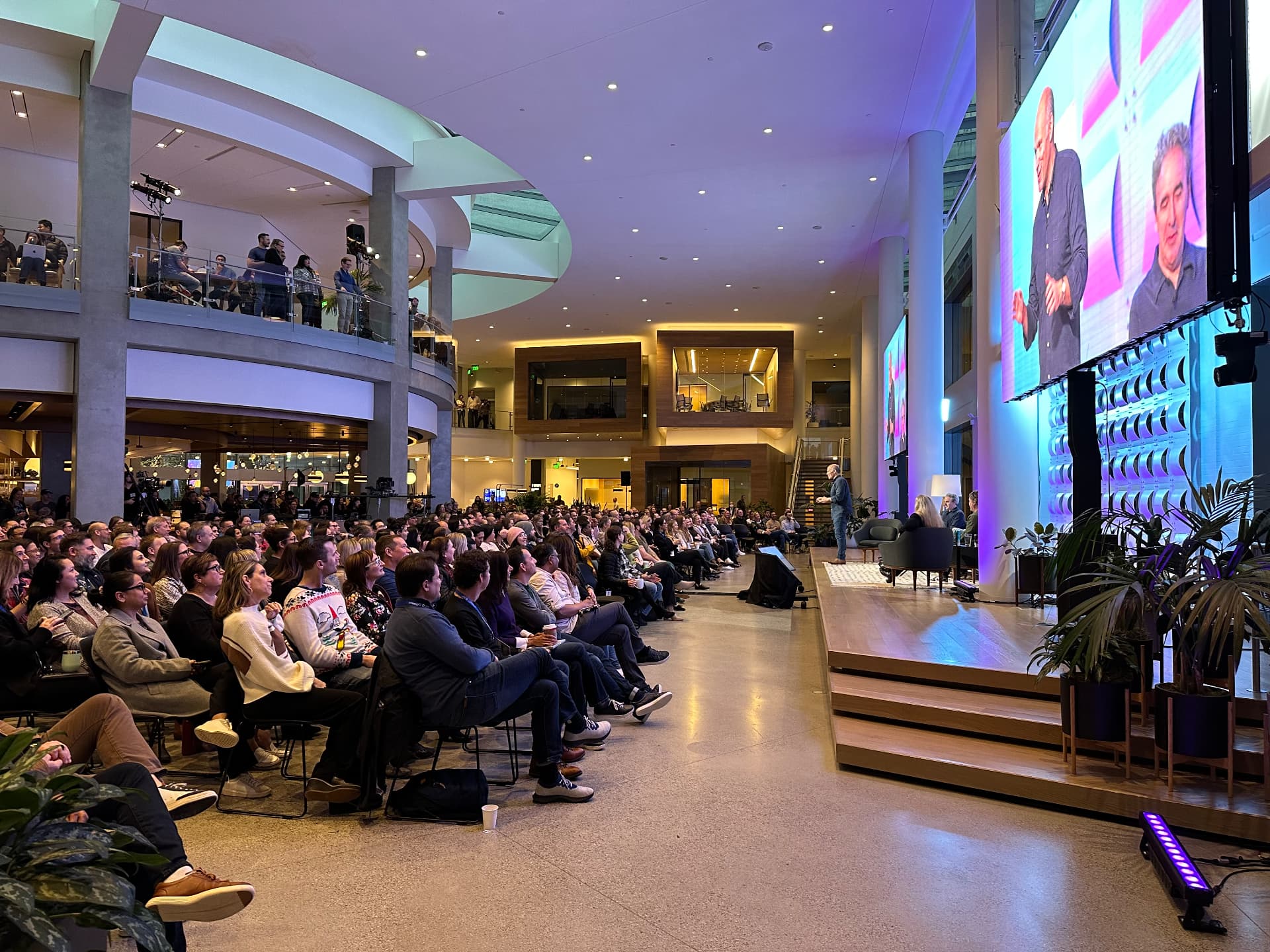 Packed atrium facing a fully produced Expedia Group broadcast